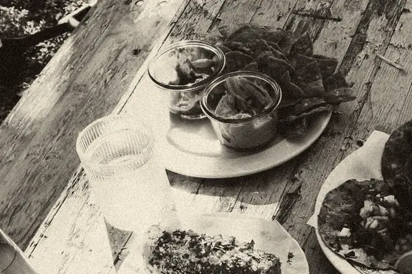 Nachos mit Guacamole und Salsa, ein gegrillter Maiskolben und ein Glas Wasser auf einem alten Holztisch.